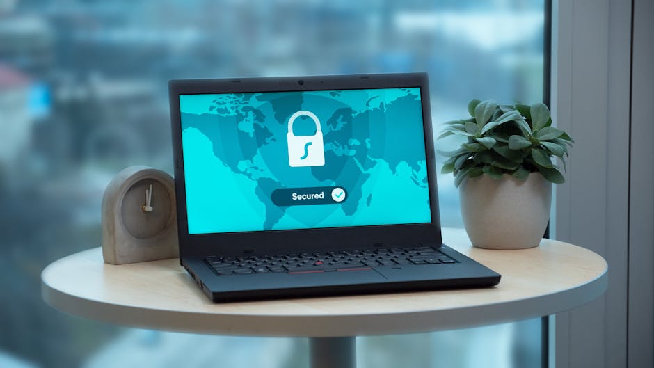 Laptop z ikoną kłódki na ekranie stoi na stole obok rośliny.