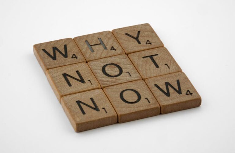 Drewniane płytki z literami ułożone w słowa "WHY", "NOT", "NOW".