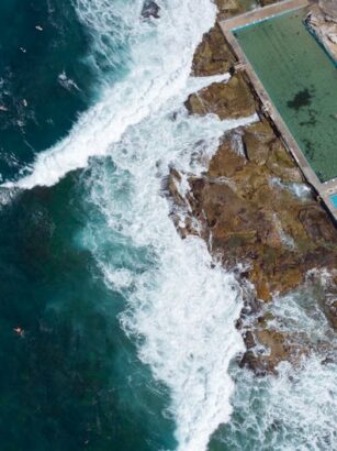Widok z lotu ptaka na baseny przybrzeżne obok wzburzonego oceanu.