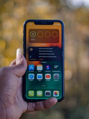 Osoba trzyma w dłoni smartfon z widocznym na ekranie widgetem stanu baterii.