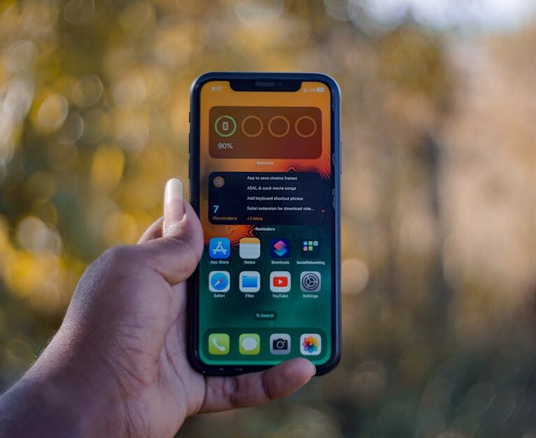 Osoba trzyma w dłoni smartfon z widocznym na ekranie widgetem stanu baterii.