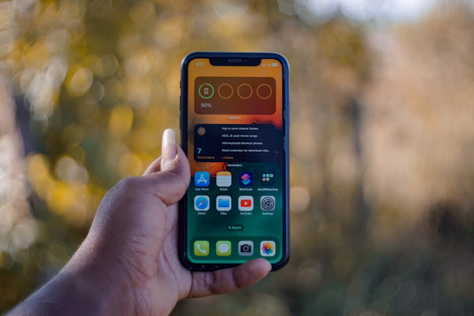 Osoba trzyma w dłoni smartfon z widocznym na ekranie widgetem stanu baterii.