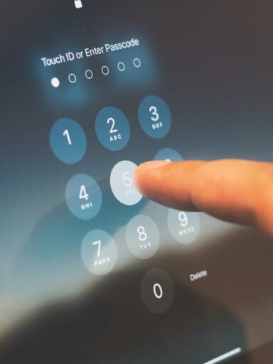 Dłoń wpisująca kod PIN na ekranie dotykowym tabletu.