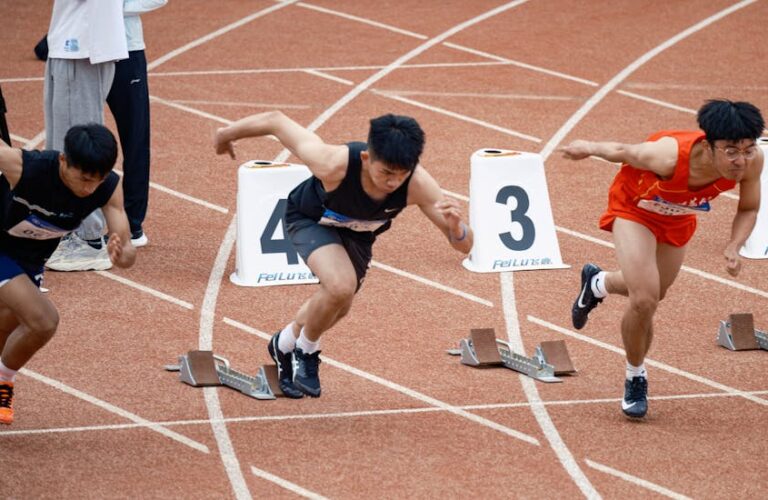 Trzech biegaczy w bloku startowym na bieżni lekkoatletycznej.