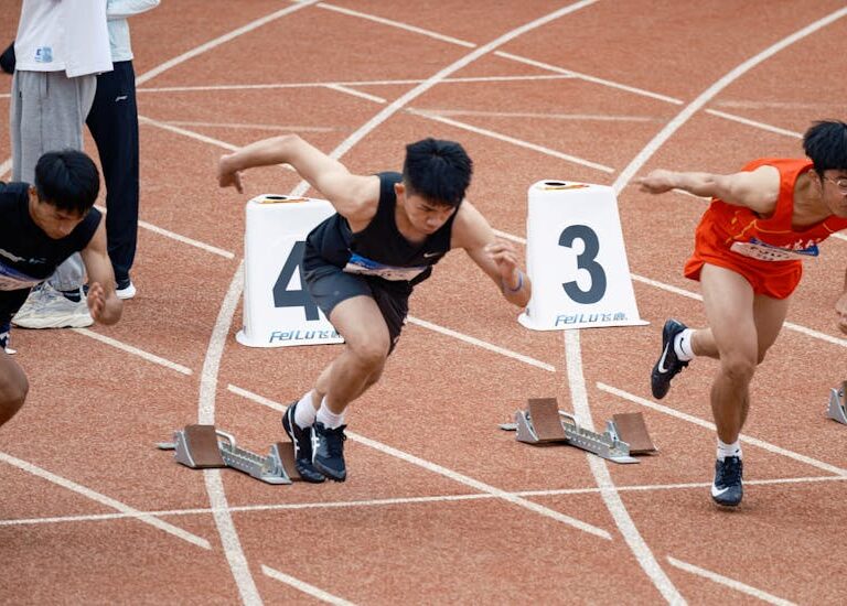 Trzech biegaczy w bloku startowym na bieżni lekkoatletycznej.