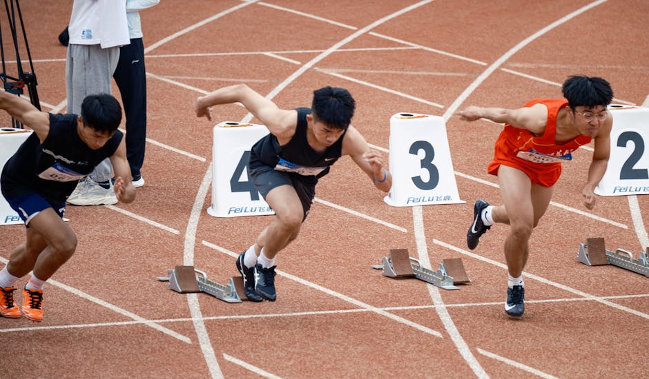 Trzech biegaczy w bloku startowym na bieżni lekkoatletycznej.