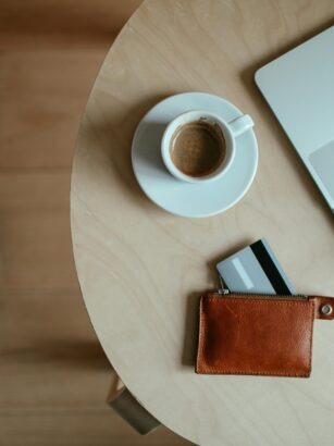 laptop, kawa i portfel z wysuniętą kartą na stoliku