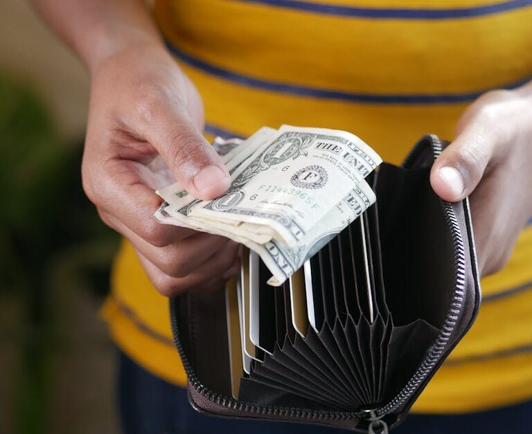 Osoba wyjmująca gotówkę z portfela.
