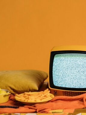 stary mały telewizor i przekąski na pomarańczowym tle