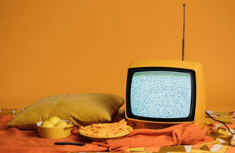 stary mały telewizor i przekąski na pomarańczowym tle