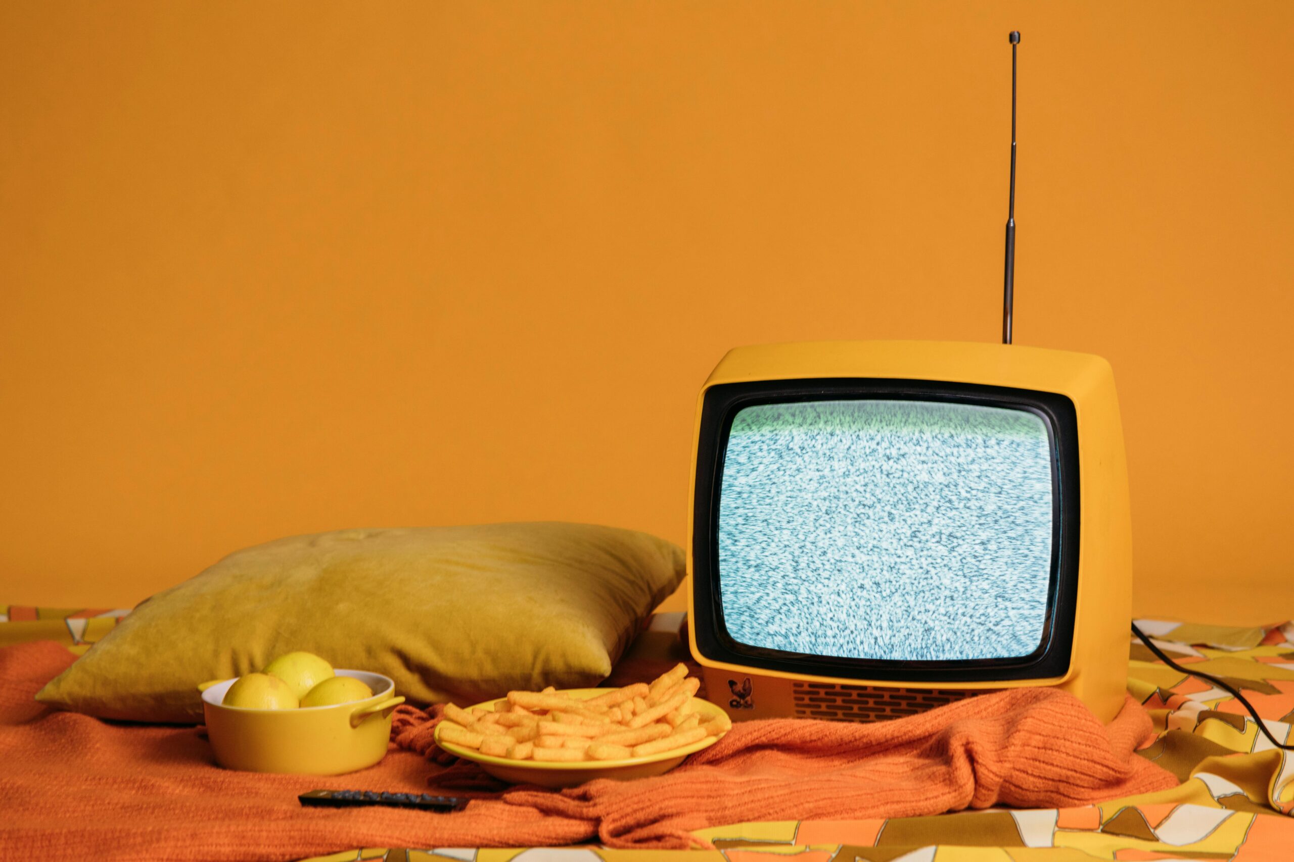 stary mały telewizor i przekąski na pomarańczowym tle