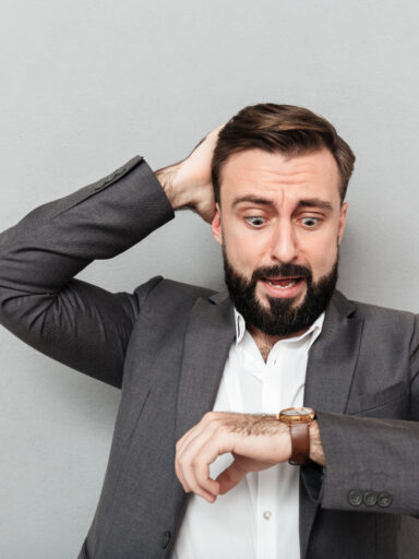 mężczyzna patrzący na zegarek ze zmartwieniem