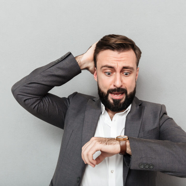 mężczyzna patrzący na zegarek ze zmartwieniem